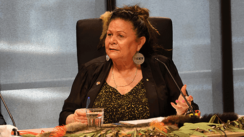 Aunty Jill Gallagher, sits at a table and gives evidence into the child protection system at a Yoorrook Public Hearing.