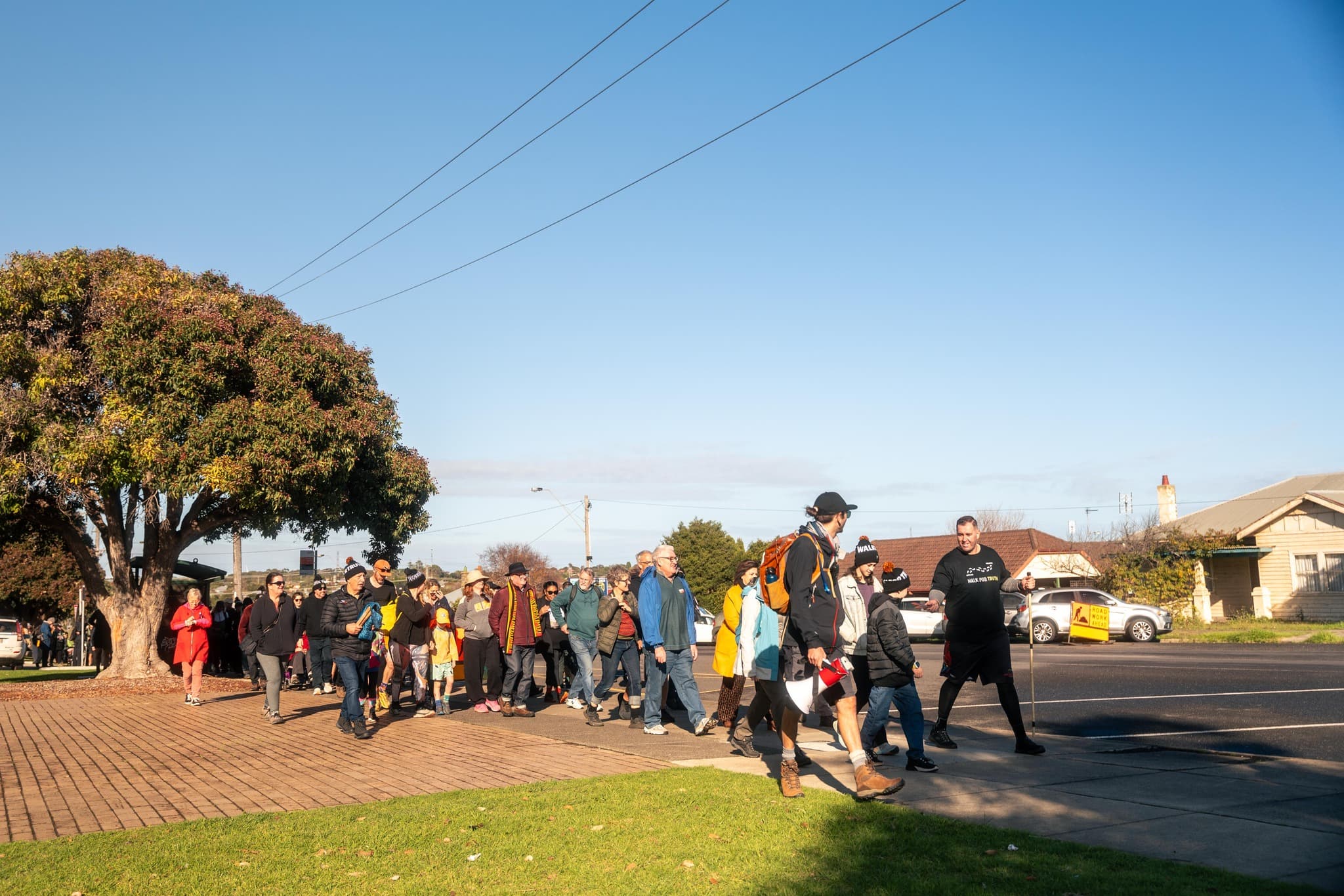 A group of people walk together through a suburban street led by Commissioner Travis Lovett on the Walk for Truth.