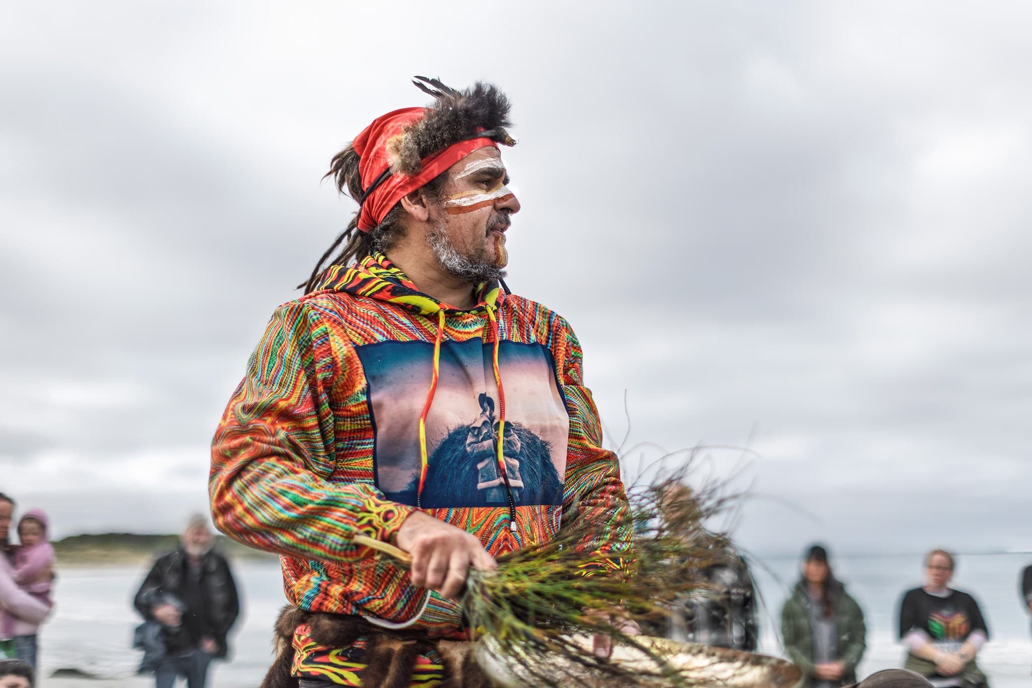 A man carries gum leaves to be used in a smoking ceremony.