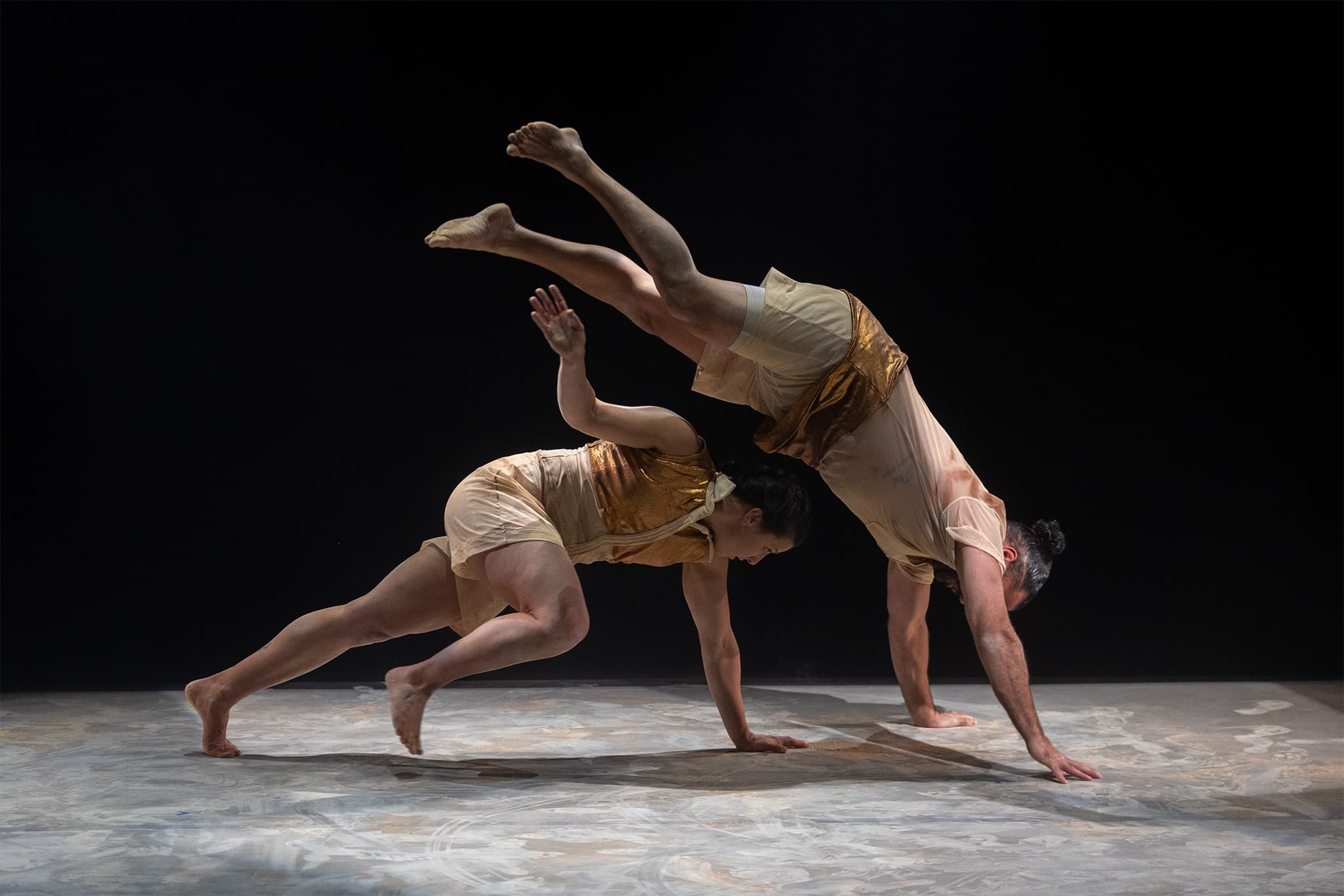 Two people from Na Djinang Circus in traditional aboriginal body paint on stage in acrobatic positions at a performance of 'The Land On Which We Meet' at Colac Otway Performing Arts and Cultural Centre.