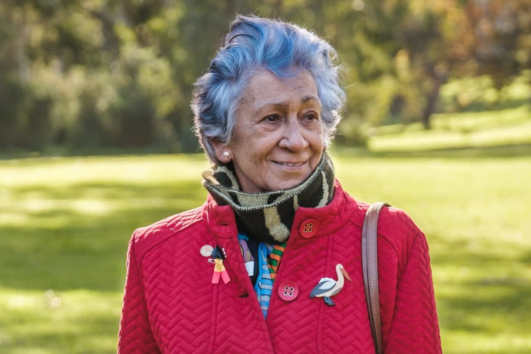 Headshot of Chair Professor Eleanor Bourke AM ourdoors with a softly blurred background of green trees and plants.
