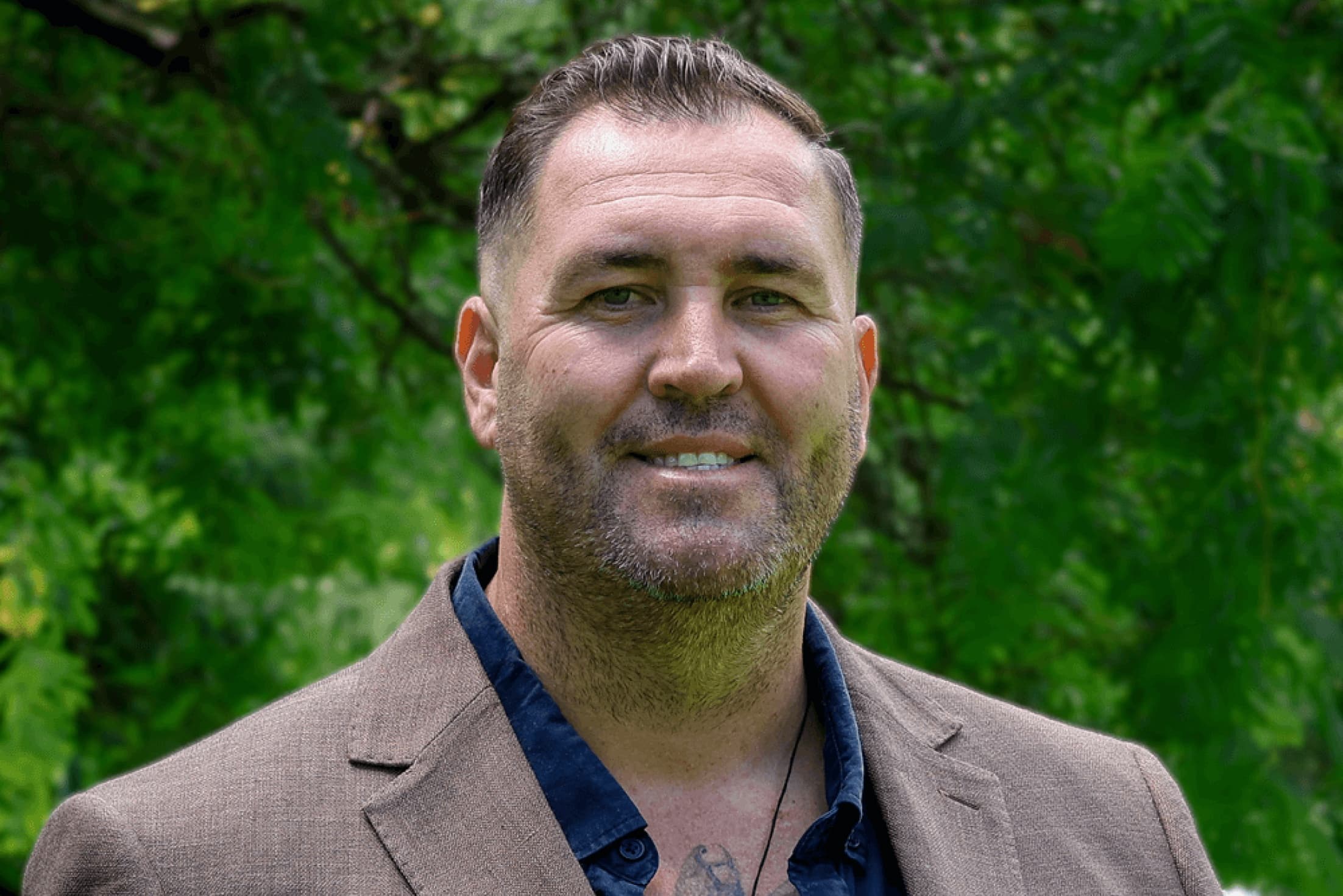 Headshot of Comissioners Travis Lovett, smiling in brown suit.