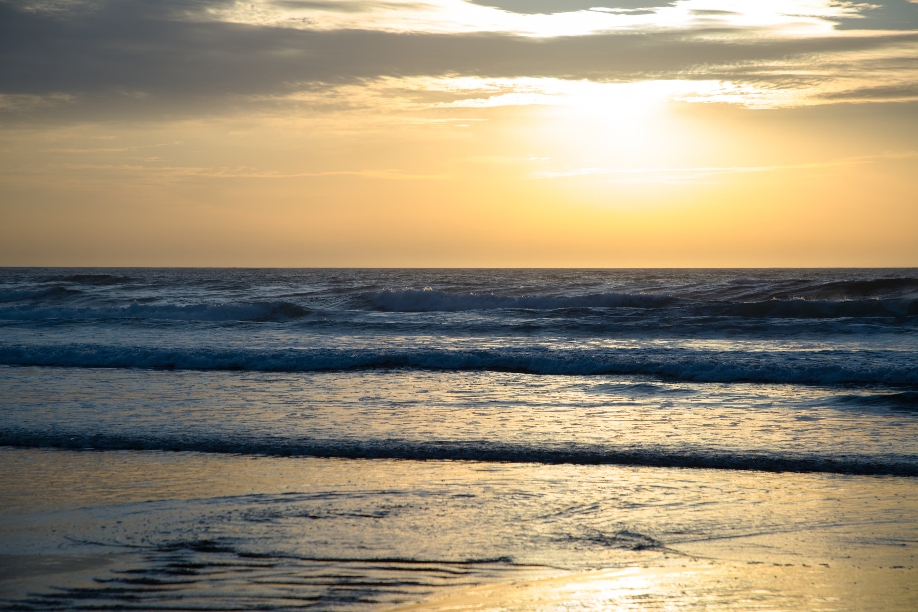 The sun setting of Wye River beach while waves gently roll over the sand.