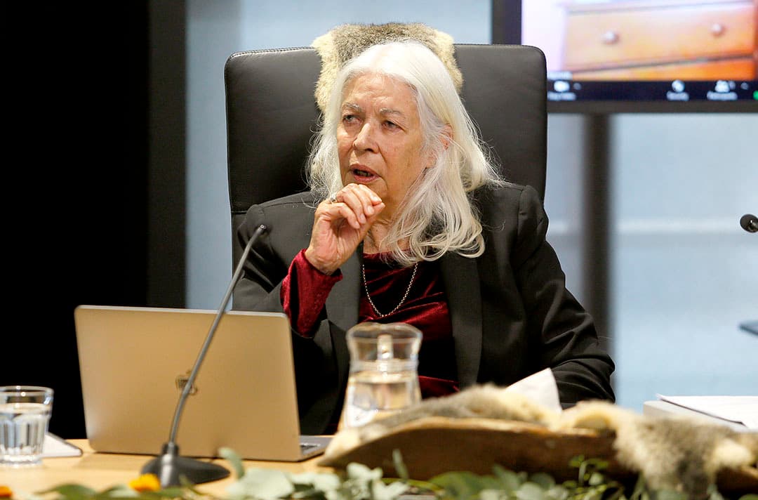 Distinguished Professor Marcia Langton from the University of Melbourne, seated in a black chair. A microphone and laptop are positioned in front of her at a Yoorrook public hearing.