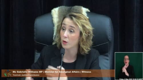 The Hon Gabrielle Williams MP talks into a microphone while seated in a black chair at a Yoorrook public hearing.