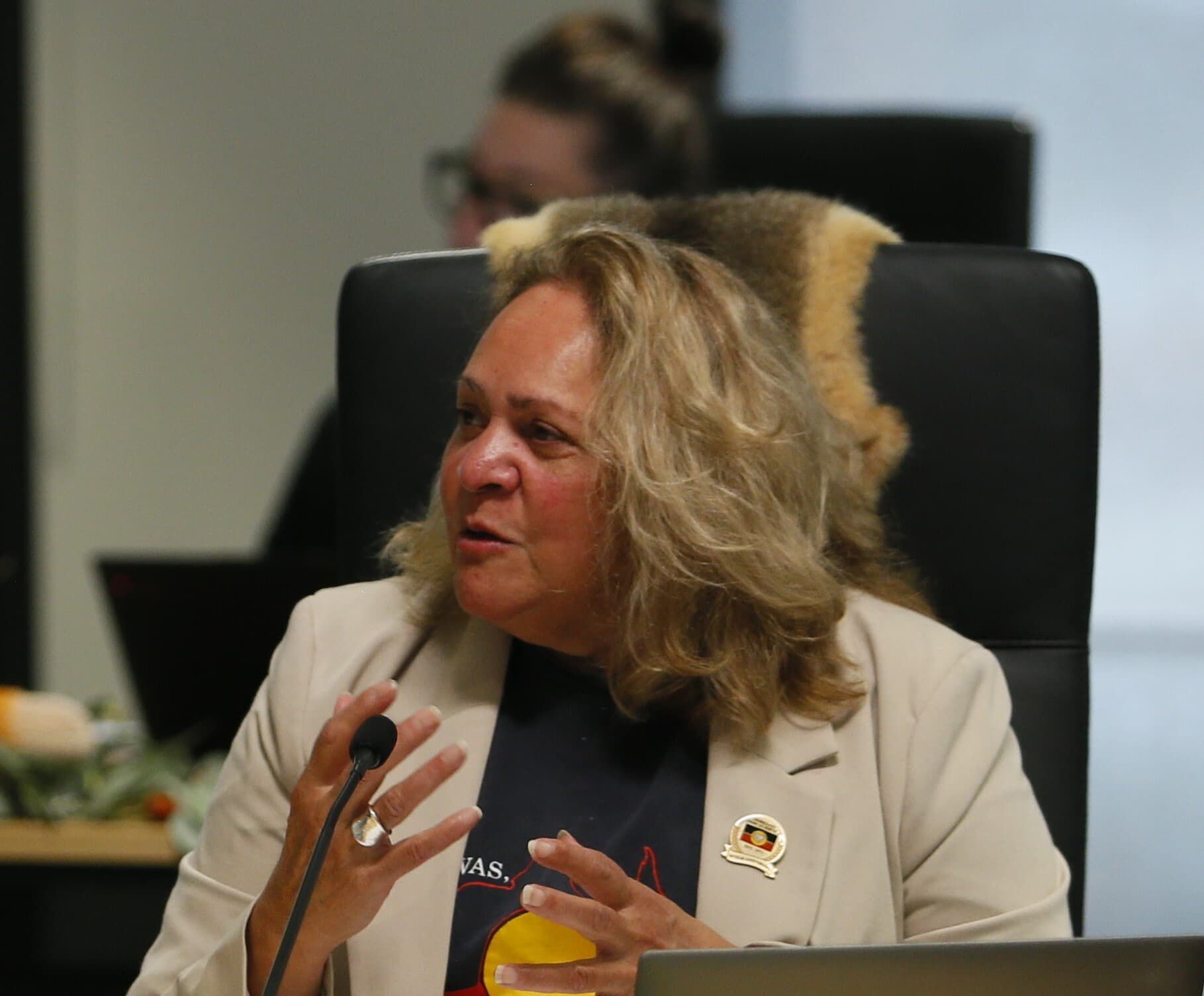 Professor Julie Andrews from La Trobe University sits in front of a microphone and gestures with her hands at a Yoorrook public hearing.