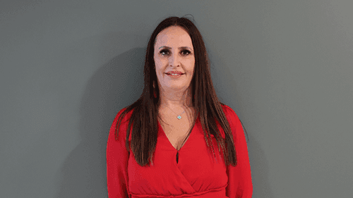 Stacey Brown from Yappera wearing a red top and standing in front of a grey wall while smiling.