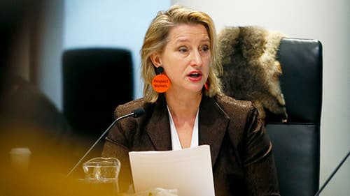 The Hon. Vicki Ward MP the Minister for the Prevention of Family Violence, seated at a chair and reading from a document she is holding in front of her.