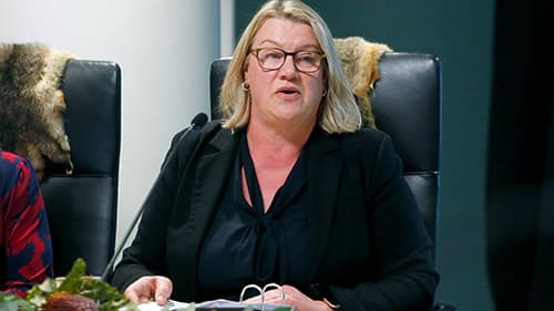 The Hon. Ingrid Stitt MP, Minister for Mental Health, seated and wearing a black suit at a Yoorrook public hearing.