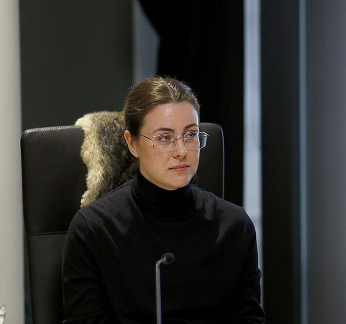 Suzannah Henty a sixth-generation patrilineal descendant of James Henty wearing a black turtle neck and sitting in front of a microphone at a Yoorrook public hearing.