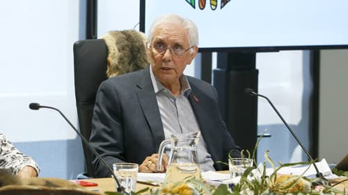 Dja Dja Wurrung and Yorta Yorta Elder Uncle Graham Atkinson wearing a grey suit and speaking while seated indoors at a Yoorrook public hearing.